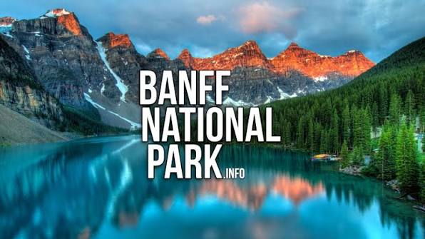 Banff National Park valley with a turquoise alpine lake, evergreen forest and snow-dusted Rocky Mountain peaks at dawn