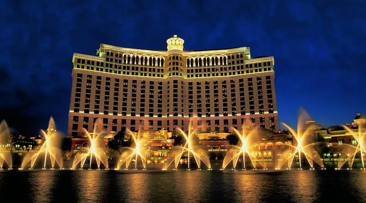 The Bellagio hotel lit up at night with its golden dancing fountains on the lake