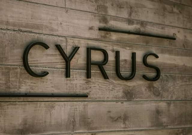 Raised black CYRUS lettering on a weathered wooden wall at the restaurant