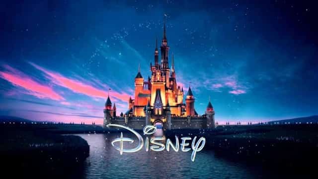 Illuminated Disney castle at twilight with stars and the Disney logo