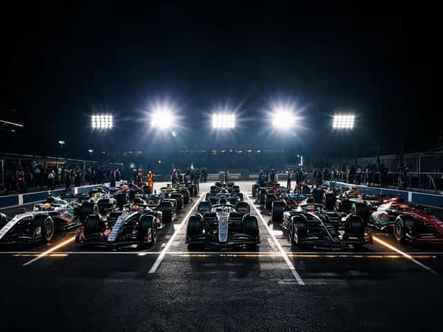 Formula 1 cars lined up on the starting grid under bright stadium floodlights at a night race