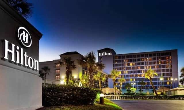 A Hilton resort hotel at night with illuminated signage and palm trees under a deep-blue terracotta