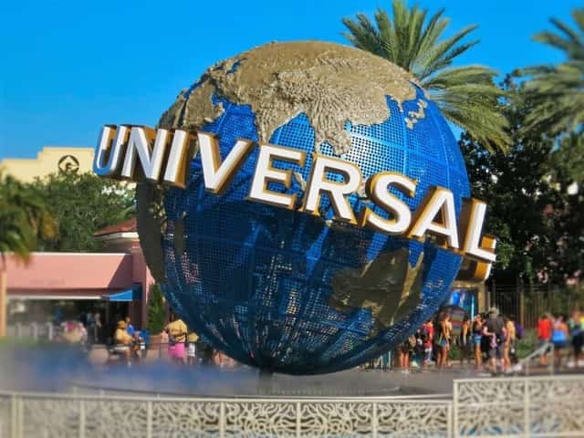 The blue UNIVERSAL globe fountain at Universal Studios with palm trees under clear terracotta