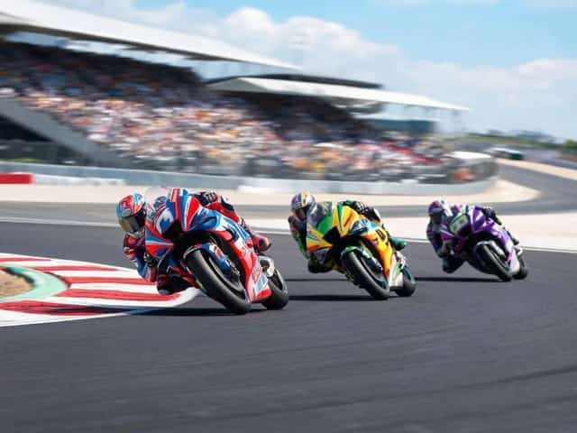 MotoGP motorcycle riders leaning hard into a circuit corner with grandstands behind