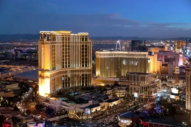 The Palazzo tower glowing gold at blue-hour dusk, the Venetian and Strip skyline behind