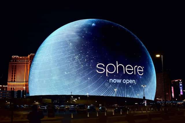 The Sphere Exosphere glowing blue with a star-field "sphere now open" visual on the Las Vegas Strip at night