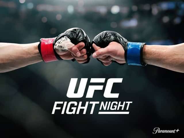 Two gloved fists touch in a UFC Fight Night touch-of-gloves moment, red and blue wrist wraps, dark arena