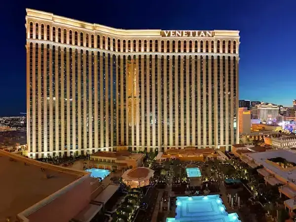 The Venetian Resort tower lit gold at dusk above illuminated resort pools in Las Vegas