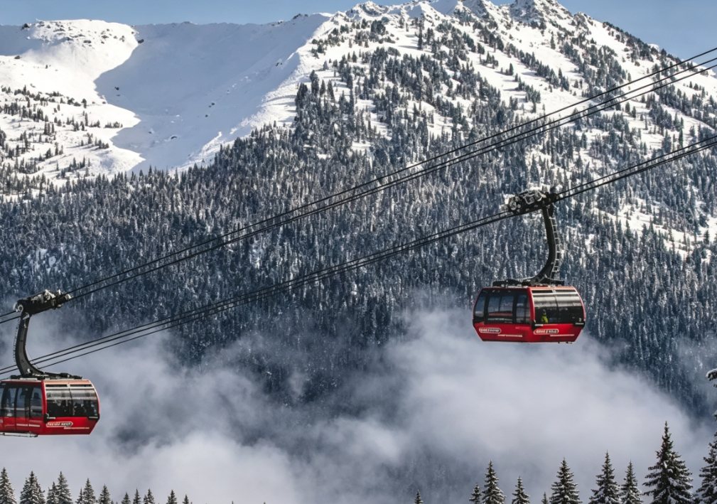 Red Peak 2 Peak gondolas gliding above cloud over snow-covered peaks at Whistler